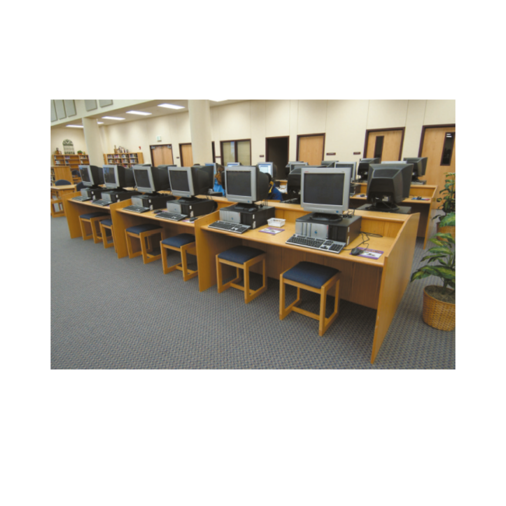 Image of a row of desks with computers on them in a library.